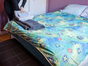 A person lays towels on a bed