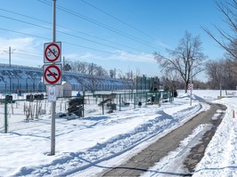 A snow-covered park with train tracks on an embankment in the background