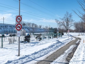 A snow-covered park with train tracks on an embankment in the background