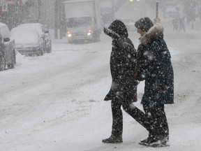 People cross Peel St. in Montreal during afternoon snowfall .