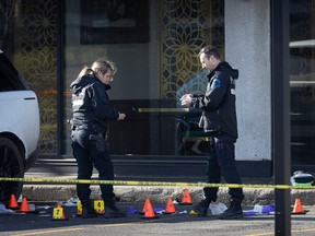 Two police officers look at a crime scene full of markers