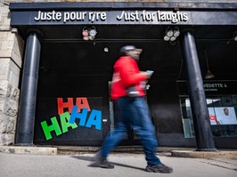 A man walks by a Just for Laughs sign