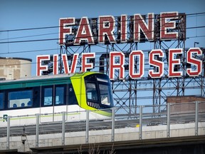 A REM train passes the iconic Five Roses flour sign in Griffintown on Friday, March 8, 2024.
