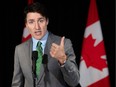 Justin Trudeau speaks at a microphone in front of Canadian flags