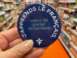 Photo from Provigo (Boucherville) Facebook page shows button some employees wear, with the words, in French: "I'm learning French; thanks for speaking slowly!"