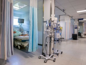A person lies in a bed in an emergency room. A curtain is obscuring their face.