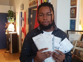 A man holds a series of tickets he received during police stops.