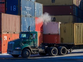 A transport truck leaves a yard of shipping containers.