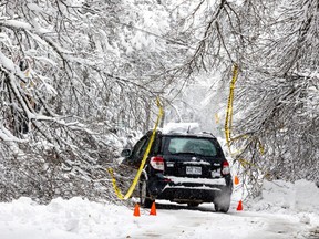 A car navigates fallen branches on a snowy road