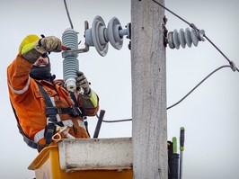 A Hydro worker works on power lines from a truck bucket.