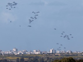 Humanitarian aid falls over northern Gaza as seen from Israel's southern border with the Gaza Strip on March 7, 2024, amid the ongoing conflict between Israel and the Palestinian group Hamas.