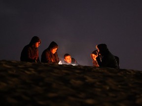 People sit by the fire at a camp for displaced Palestinians in Rafah, in the southern Gaza Strip, on the eve of the Muslim holy fasting month of Ramadan on March 10, 2024, amid ongoing battles between Israel and the militant group Hamas.