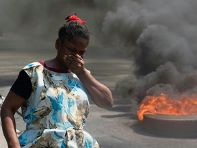 A woman walks past burning tires during a demonstration following the resignation of Prime Minister Ariel Henry, in Port-au-Prince, Haiti, on March 12, 2024.