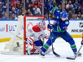 A goalie blocks the net as a player manoeuvres a puck with a stick.