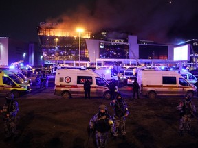 Law enforcement officers are seen deployed outside the burning Crocus City Hall concert hall following the shooting incident in Krasnogorsk, outside Moscow, on March 22, 2024.