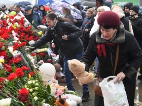 A woman places a Teddy bear at a makeshift memorial in front of the Crocus City Hall in Krasnogorsk on March 24, 2024, as Russia observes a national day of mourning after a massacre that killed more than 130 people.