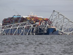 A cargo ship with the wreckage of a steel bridge on top of it.