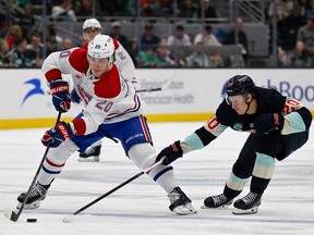 Canadiens' Juraj Slafkovsky (20) skates the puck against Eeli Tolvanen (20) of the Seattle Kraken during the first period at Climate Pledge Arena on Sunday, March 24, 2024, in Seattle.