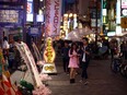 Visitors shelter from the rain under an umbrella on April 23, 2016 in the Dotonbori district of Osaka, Japan. The lively streets running along the Dontonbori Canal, are among the most iconic and popular tourist destinations in Osaka, the second largest city in Japan.