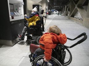 Two commuters in wheelchairs attempt to buy tickets from the self-serve ticket dispenser at the REM station at Central Station on Friday, Feb. 16, 2024.