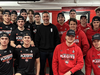 A team of junior hockey players wearing red and black shirts that advertise the playoffs in English only