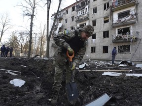 A police officer inspects a crater in front of a damaged residential building that was hit by a Russian strike in Kharkiv, Ukraine, Wednesday, March 27, 2024.