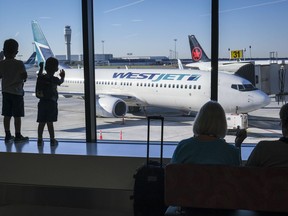 Young boys look out at Air Canada and WestJet planes at Calgary International Airport in Calgary on Aug. 31, 2022.