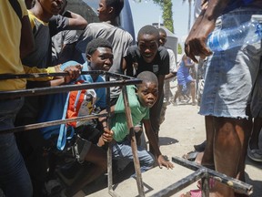 Youth take cover after hearing gunshots at a public school that serves as a shelter for people displaced by gang violence, in Port-au-Prince, Haiti, Friday, March 22, 2024.