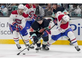 Kraken's Kailer Yamamoto (56) battles for the puck against Canadiens' Alex Newhook, left, and defenceman Kaiden Guhle (21) on Sunday, March 24, 2024, in Seattle.