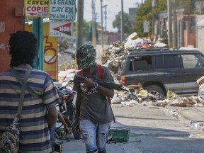 Armed members of the G9 and Family gang stand guard at their roadblock in the Delmas 6 neighborhood of Port-au-Prince, Haiti, Monday, March 11, 2024.