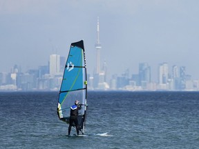 A windsurfer cuts through the waves along Lake Ontario overlooking the City of Toronto skyline on a warm winter day in Mississauga, Ont., Friday, Feb. 9, 2024.