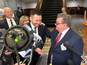 Denis Coderre puts his hand on the shoulder of Parti Québécois Leader Paul St-Pierre Plamondon in front of reporters at the National Assembly.