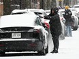 People clear snow from their cars during heavy snowfall in Montreal on Dec. 3, 2023.