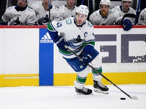 Canucks defenceman Quinn Hughes is seen with the puck on his stick at the opponents' blue line.