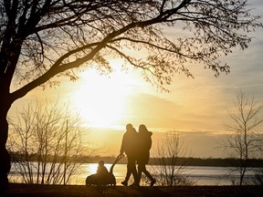 A family walks by a body of water as the sun sets
