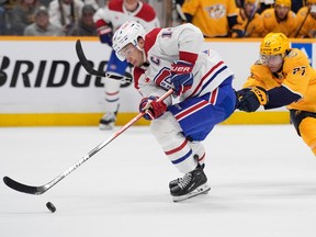 Canadiens centre Nick Suzuki skates the puck past Predators winger Luke Evangelista .