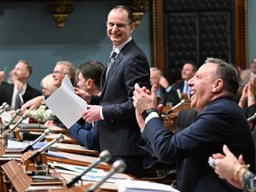 Quebec Finance Minister Eric Girard pauses as he presents his provincial budget, at the legislature in Quebec City, Tuesday, March 12, 2024. Quebec Premier Francois Legault, right, applauds.