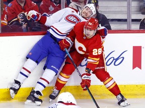Canadiens' Joel Armia, left, takes a hit from Flames' Nikita Okhotiuk in Calgary on Saturday, March 16, 2024.