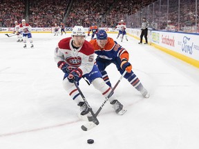 Canadiens' Jordan Harris, front, and Oilers' Corey Perry battle for the puck during a game Tuesday night in Edmonton.