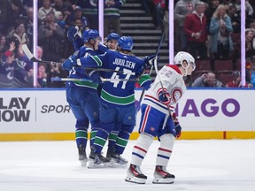 Vancouver Canucks' Nikita Zadorov, back left, Noah Juulsen (47) and Ilya Mikheyev celebrate Zadorov's second goal as Montreal Canadiens' Cole Caufield (22) skates by