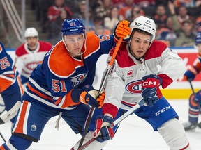 An Edmonton Oilers player pushes into a Montreal Canadien with his stick