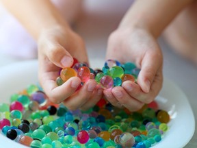 A pair of hands holds a pile of gel balls above a dish with more of them