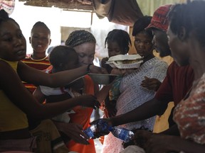 Women scuffle for plates of food for their children at a shelter for families displaced by gang violence, in Port-au-Prince, Haiti, Friday, March 22, 2024.