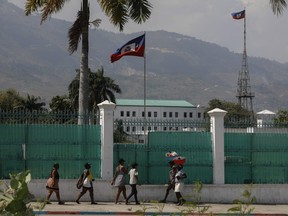 People walk past the National Palace in Port-au-Prince, Haiti, Monday, March 25, 2024.