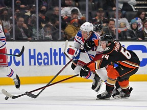 Rangers' Kevin Rooney and Ducks' Jacob Perreault, right, chase down the puck during a game in Anaheim in 2022.