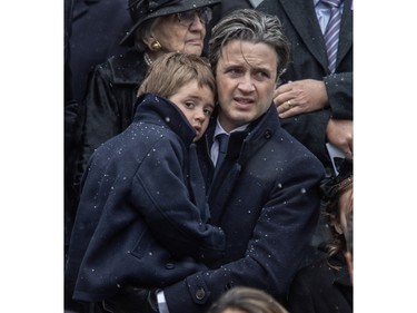Nicolas Mulroney, son of Brian Mulroney, holds a child as the casket of former prime minister Brian Mulroney is taken away at Notre-Dame basilica on Saturday, March 23, 2024.