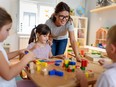 A teacher with children playing with colorful wooden didactic toys