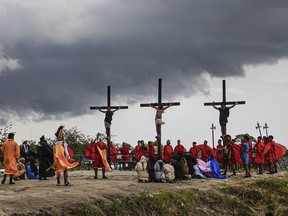 Ruben Enaje, centre, is seen on a cross flanked by two other devotees during a re-enactment of Jesus Christ's sufferings as part of Good Friday rituals in San Pedro Cutud, north of Manila, Philippines, Friday, March 29, 2024.