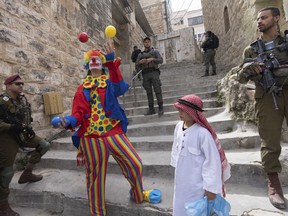 Jewish settlers dressed in costumes celebrate the holiday of Purim as soldiers secure the area in the West Bank city of Hebron, March 7, 2023.