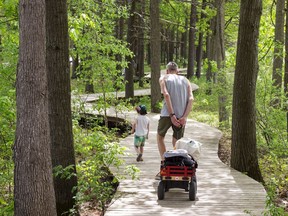 A man and his son walk along the boardwalk toward the beach at Oka provincial park on May 28, 2020, in Montreal.